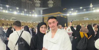 Momen berikutnya memperlihatkan keduanya berpose mesra di depan Ka'bah. Putri Zulhas tampil anggun dalam gamis putih dengan aksen renda emas yang memberikan kesan mewah namun tetap sopan.  [@zumizolazulkiflinurdin].